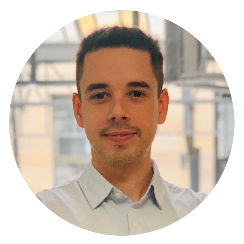Man in a light blue shirt smiling indoors.